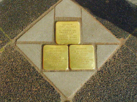 Drei Stolpersteine mit eingravierten Namen und Daten in einem Pflasterfeld