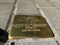 Stolperstein mit eingraviertem Text in einem Gehweg aus Pflastersteinen